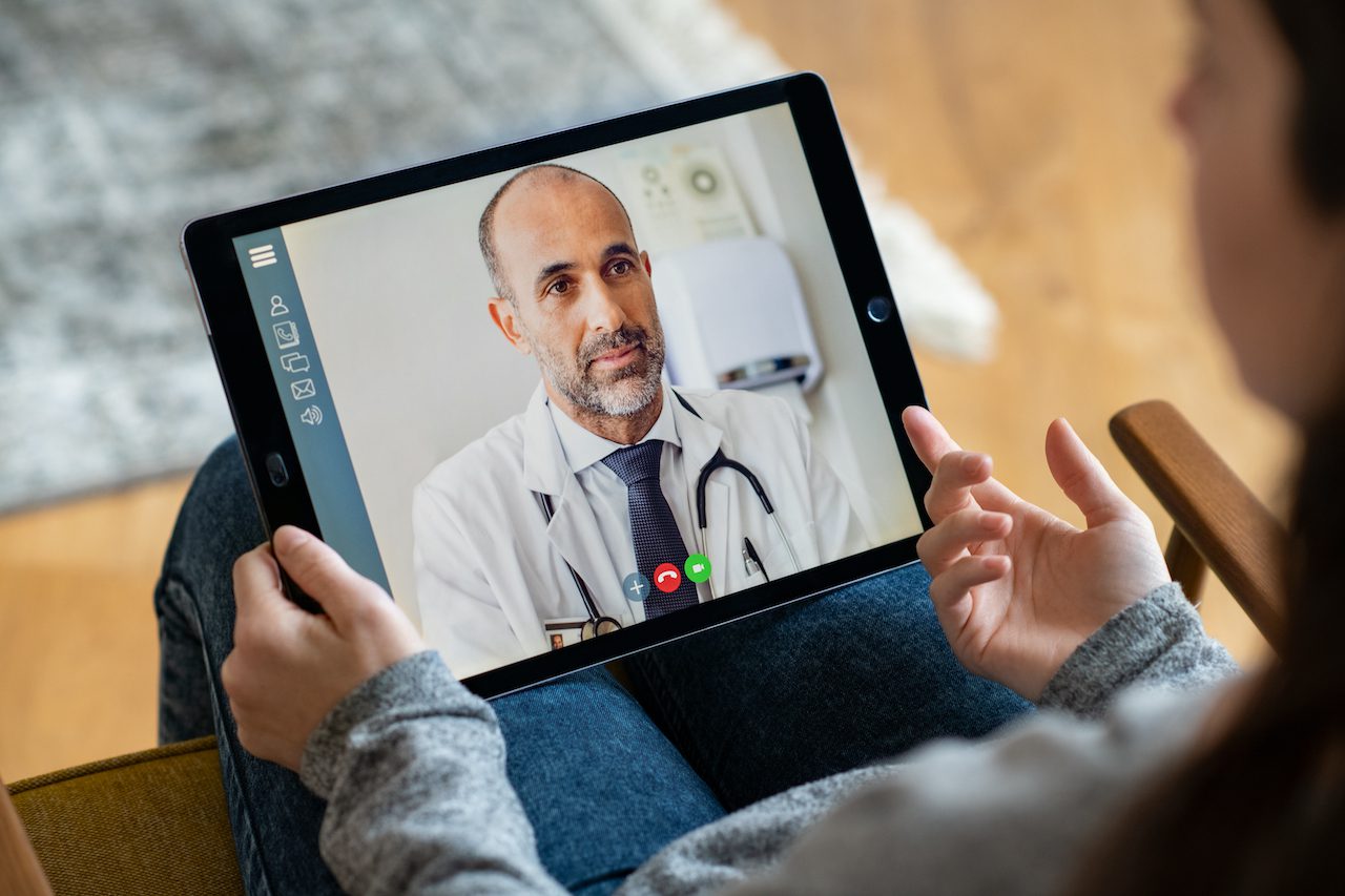 Patient having a telehealth consultation with a doctor on a tablet, representing QuickMD's telehealth addiction services