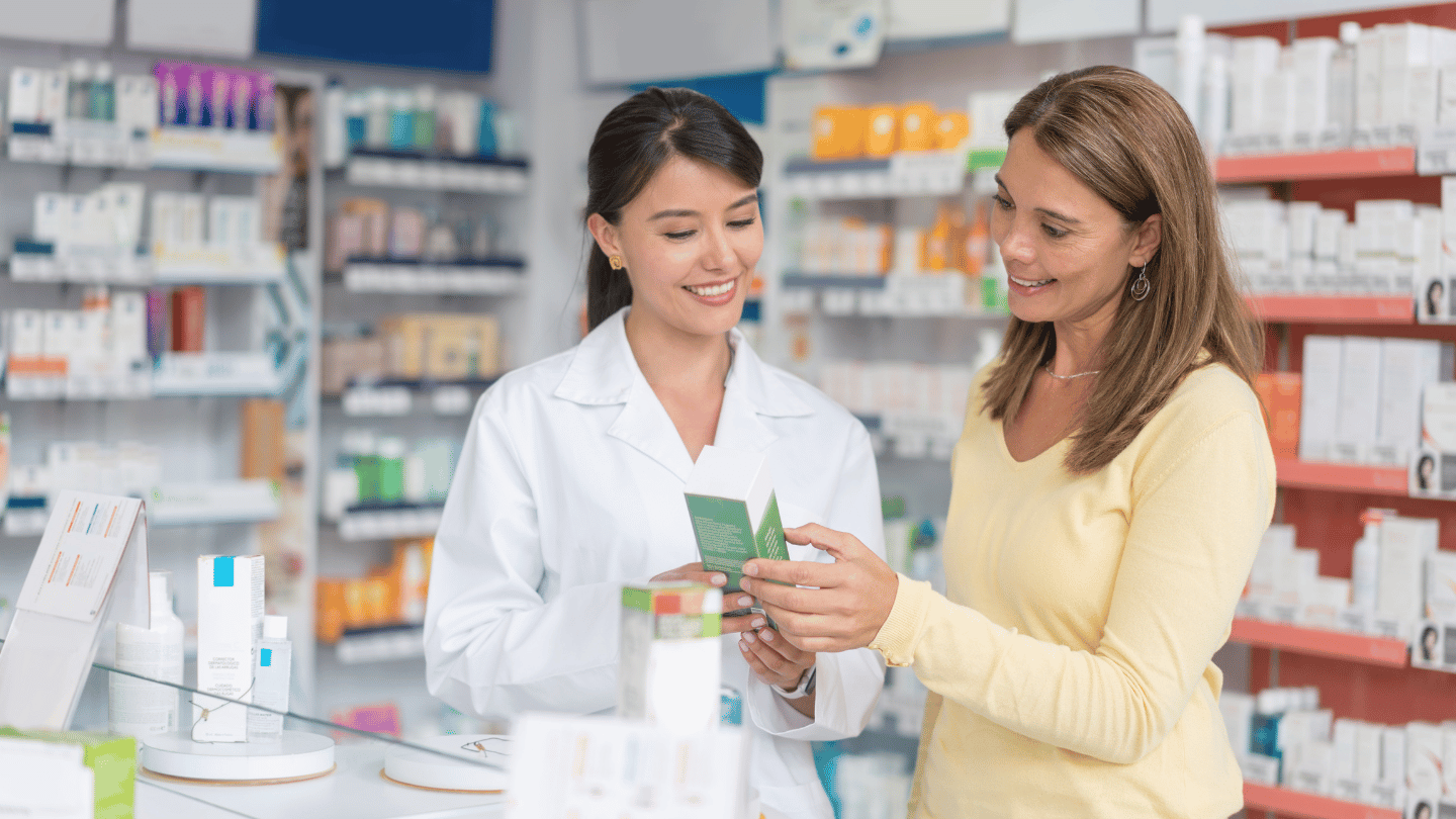 A pharmacist assisting a customer with information about weight loss injection costs at a pharmacy counter