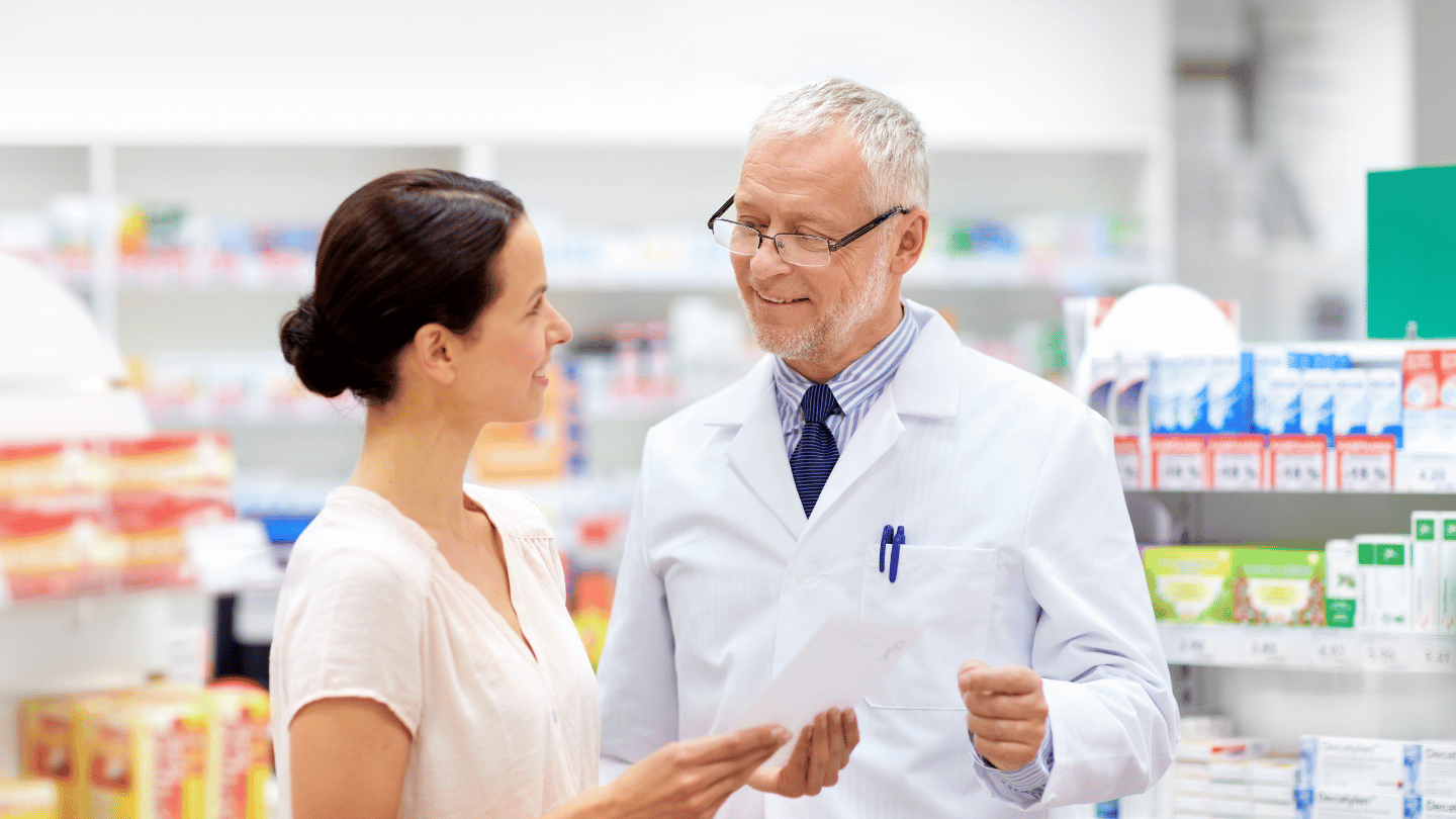 Pharmacist discussing prescription with a female customer in a pharmacy, highlighting the importance of professional consultation for medications like Ozempic