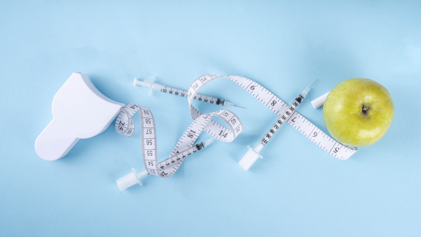 Image of a tape measure wrapped around syringes and an apple, symbolizing weight loss, diet control, and the use of compounded semaglutide injections for effective weight management