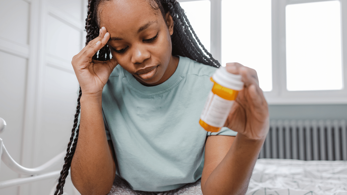 Woman experiencing Subutex side effects while holding a medication bottle