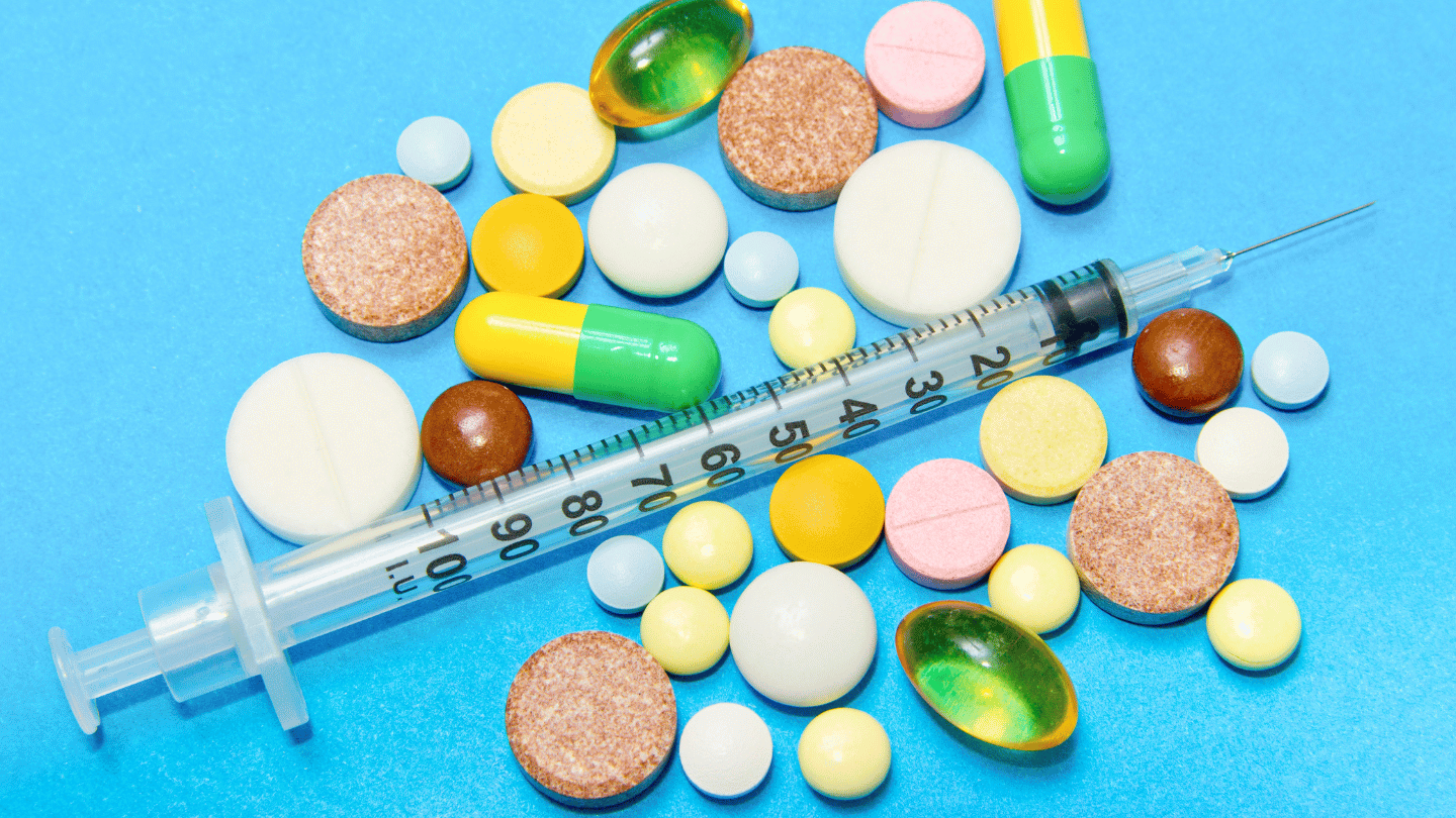 Various pills and a syringe representing medication-assisted treatment options like Suboxone and Belbuca for opioid addiction recovery