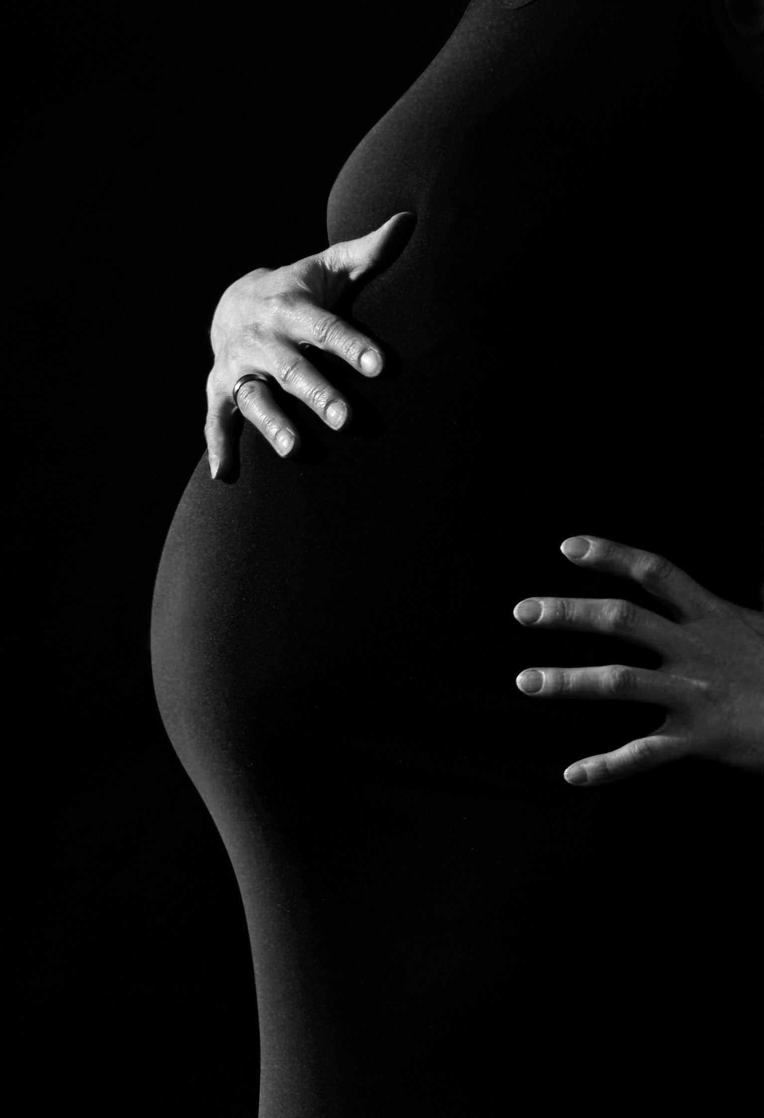 Woman holding her pregnant belly after experiencing bleeding during early pregnancy